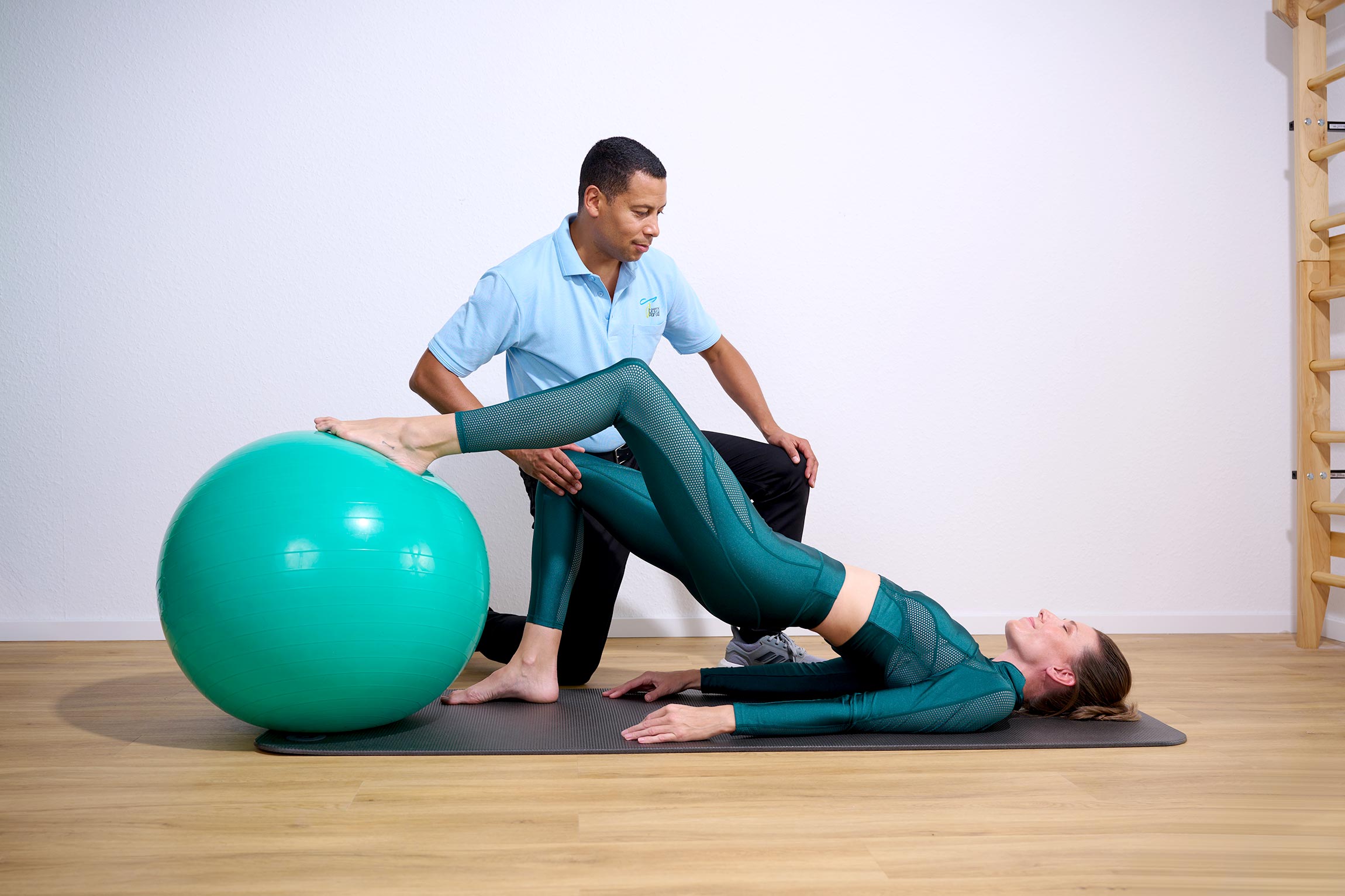 Physiotherapeut behandelt eine Patientin auf der Matte